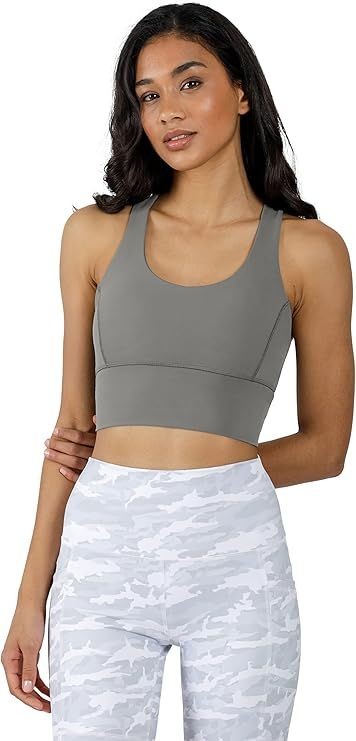 Woman in a gray sports bra and white camo leggings posing against a white background.